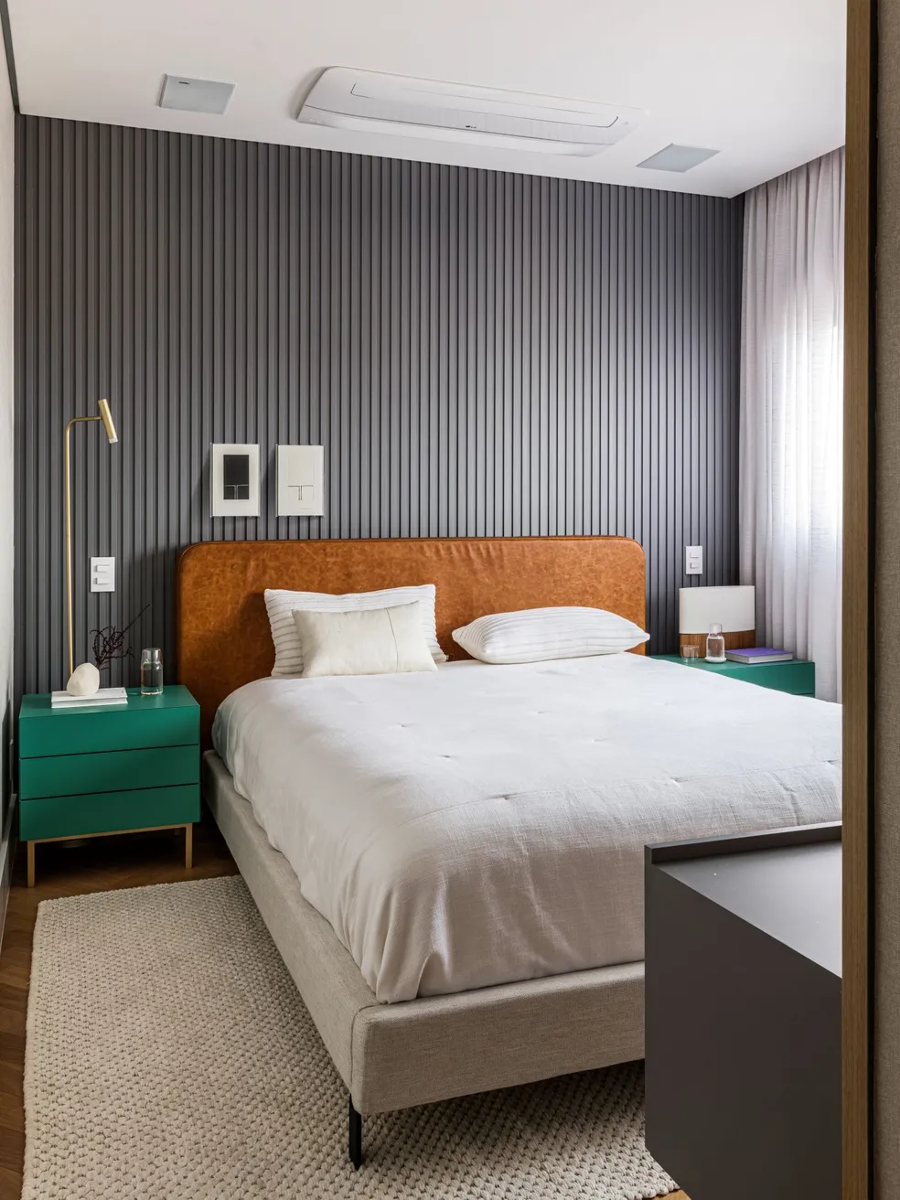 Quarto principal com cama de casal, quadros na parede e mesas de apoio